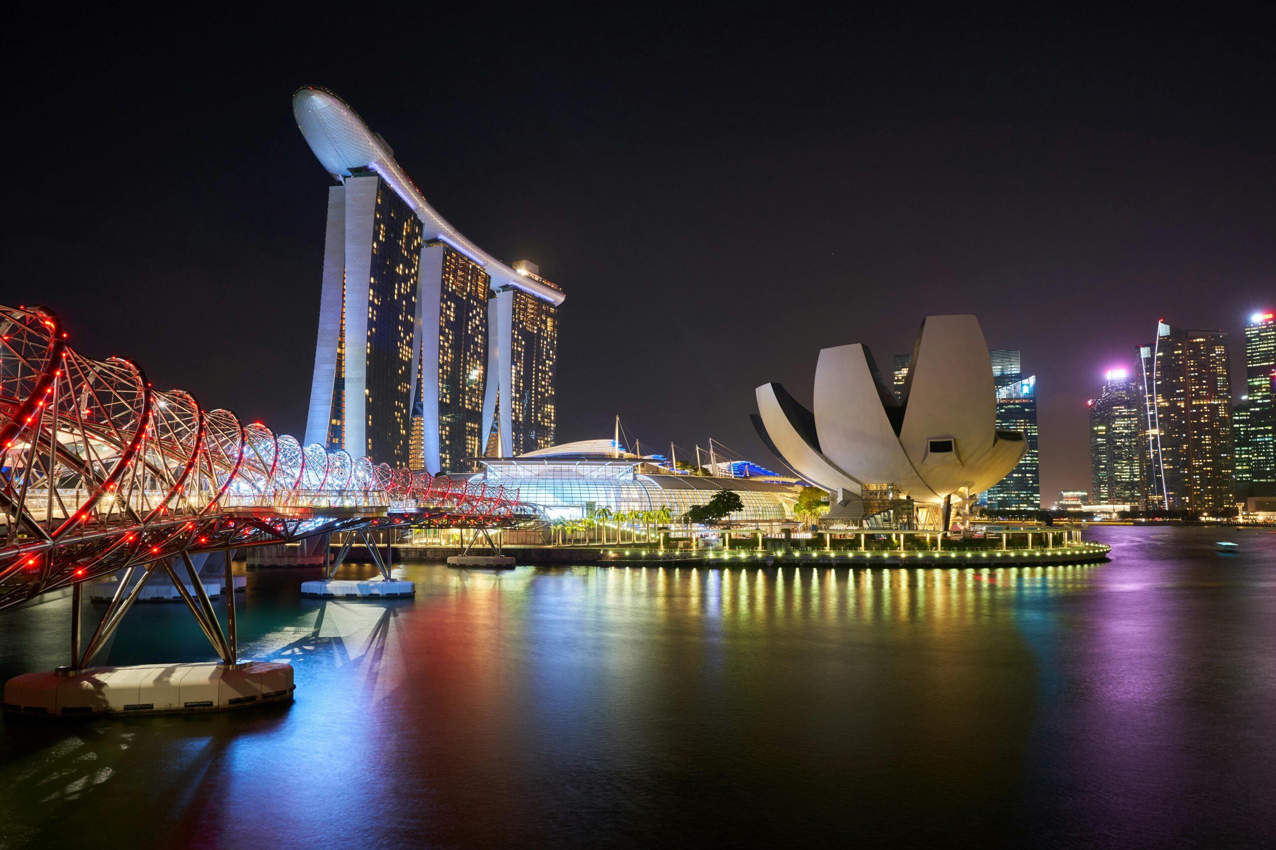 Home Stunning night view of Marina Bay Sands and Helix Bridge illuminated over water in Singapore.
